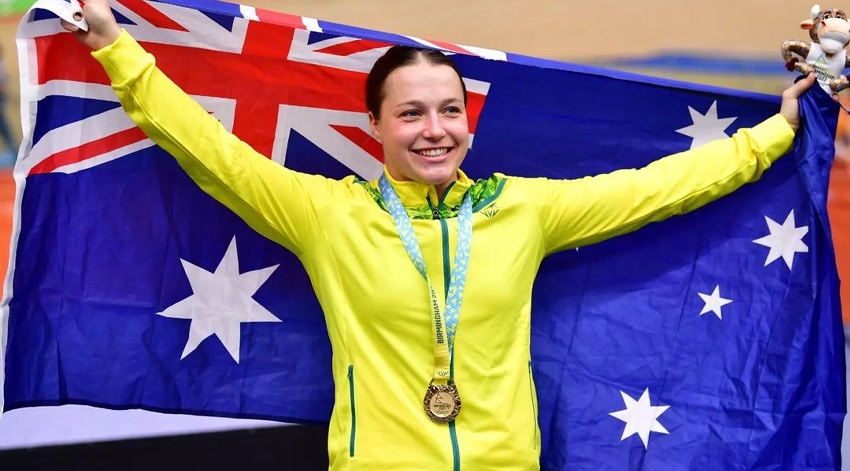 Australian athlete wearing a yellow jacket, celebrating with an Australian flag and a gold medal.