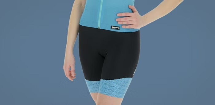 Woman Wearing Black Cycling Shorts with Blue Trim and Blue Jersey on a Blue Background